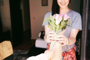 Frau bekommt einen Tulpenstrauß als Geschenk überreicht